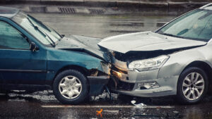 Car accident on wet road during rain, head on collision side view. Two cars damaged after head-on collision, car crash. Car crash on the street, damaged cars after collision. Traffic rules violation