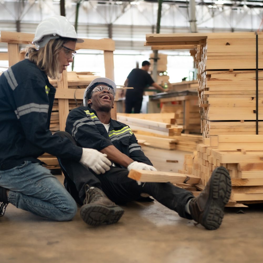 Foreman technician injured at leg from accident crying with pain in warehouse. Female engineer emergency help colleague who falling down get physical injury in workplace. Risk, dangerous in workplace.